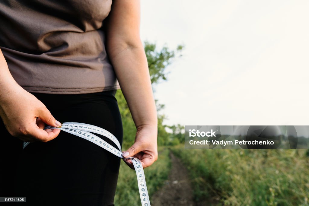 Woman measuring her thigh with measure tape Weight loss, diet, motivation and healthy lifestyle. Overweight woman measuring her thigh with measure tape Abdomen Stock Photo