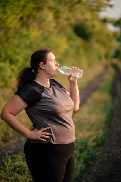 istock Overweight woman drinking water after workout 1167244685