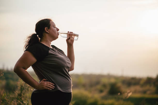 übergewichtige frau trinkwasser nach dem training - fett nährstoff stock-fotos und bilder