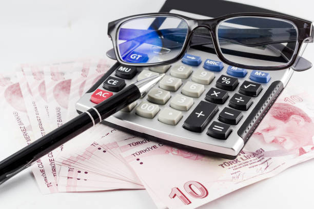istock Turkish Money Banknotes on the white surface with pen,glasses and calculator. 1167244982