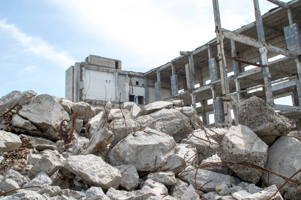 detriti grigi di cemento da vicino sullo sfondo dei resti dell'edificio distrutto contro il cielo. sfondo - quake damaged section foto e immagini stock