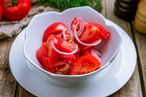 Tomato salad with red onion on wooden table