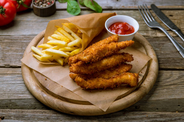 Chicken strips with ketchup Chicken strips with ketchup and french fries on old wooden table chicken finger stock pictures, royalty-free photos & images