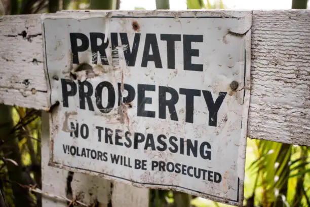 No trespassing private property, violators will be prosecuted sign. Old, damaged, rusted, metal, white with black text.
