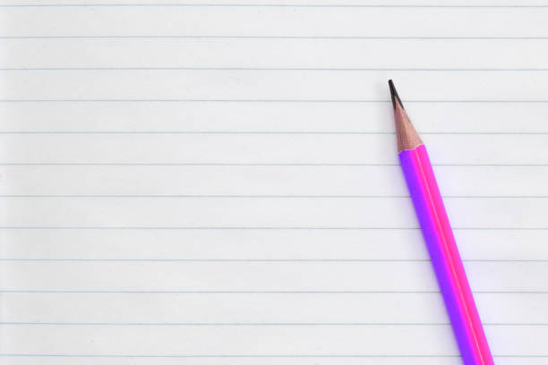 A minimalist notecard rests on a blue surface. The card features a subtle border and a small decorative floral emblem at the bottom center. A white pencil lies diagonally across the card, casting a soft shadow. The overall composition is simple, with an emphasis on clean lines and a neutral color palette, making it suitable for journaling or branding purposes.