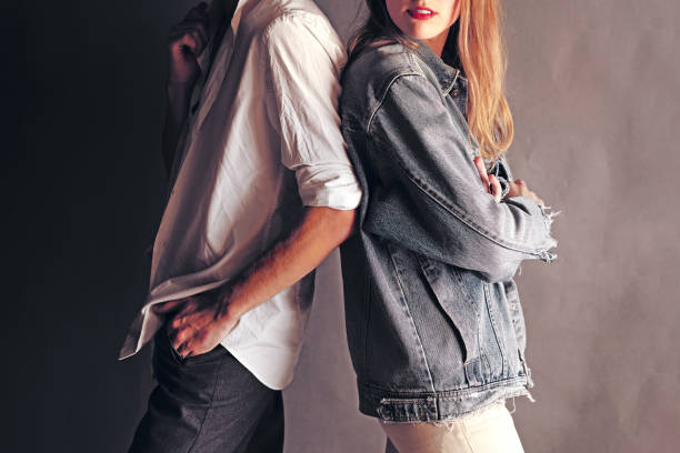 happy young couple back to back each other on a grey wall background. couple ignoring each other while standing back to back - clothing casual concepts love imagens e fotografias de stock