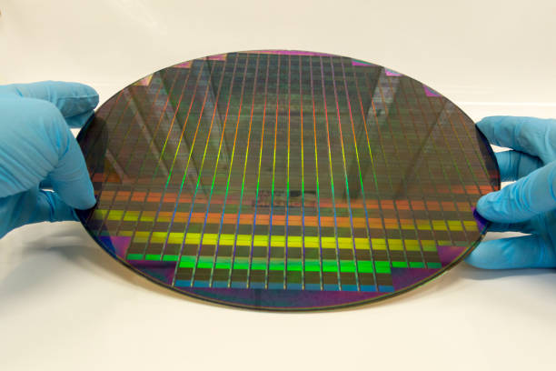 istock Two Gloved Hands Holding a Patterned 12 Inch 300 mm Silicon Wafer Against a White Background 1167267120