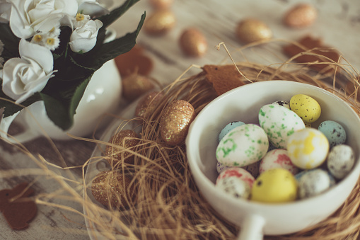 Easter table decoration - quail eggs, bunny shaped decorations, and flower arrangement on rustic table.