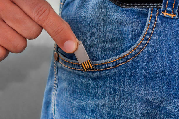 istock man putting usb stick in his pocket jeans. Flash memory drive in hand 1167277699