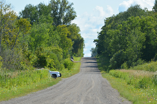 Landscape of a country road with a police car hiding at bottom of hill
