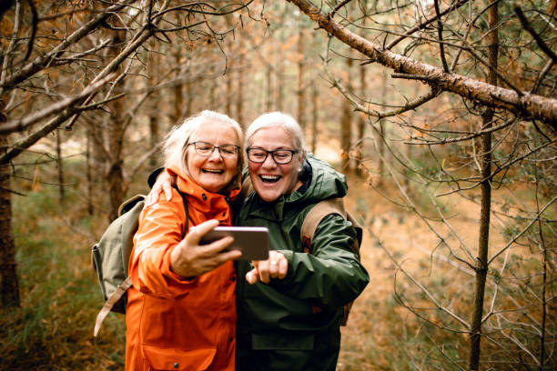 Seniors taking a Selfie Close up of two female seniors taking a selfie while hiking in the forest raincoat photos stock pictures, royalty-free photos & images