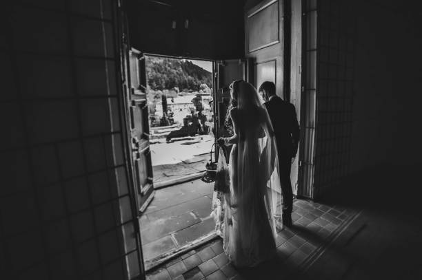 istock Bride and groom go back exit from the church after wedding ceremony. Black and white photo. 1167304429