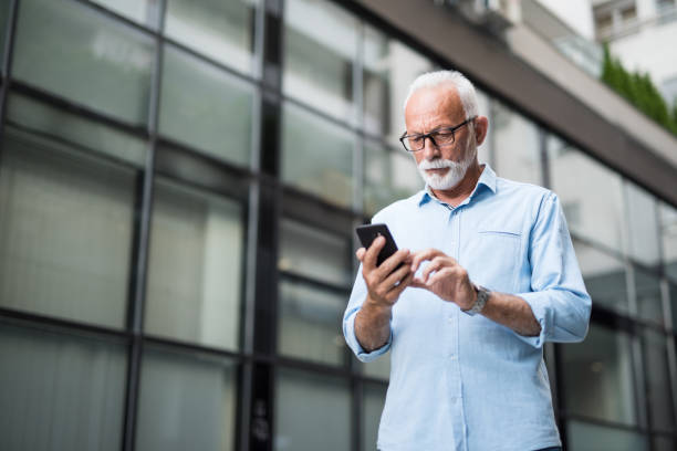 istock Serious senior businessman using phone outdoors. 1167309033