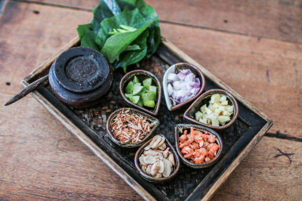 istock Thai Food Miang Kum Leaf-Wrapped Bite-Size Appetizer,A hand holdind a Leaf-Wrapped Bite-Size Appetizer. A Thai snack set of Wild Betel Leaf bush leave with ingredients chopped or cut into small pieces 1167319675