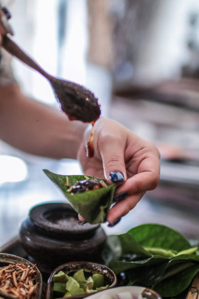 istock Thai Food Miang Kum Leaf-Wrapped Bite-Size Appetizer,A hand holdind a Leaf-Wrapped Bite-Size Appetizer. A Thai snack set of Wild Betel Leaf bush leave with ingredients chopped or cut into small pieces 1167319676