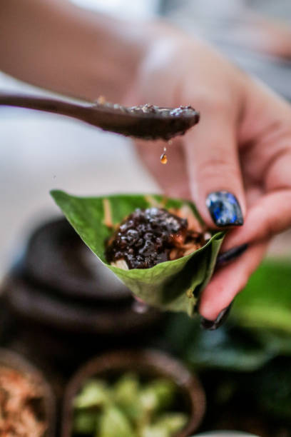 istock Thai Food Miang Kum Leaf-Wrapped Bite-Size Appetizer,A hand holdind a Leaf-Wrapped Bite-Size Appetizer. A Thai snack set of Wild Betel Leaf bush leave with ingredients chopped or cut into small pieces 1167319679