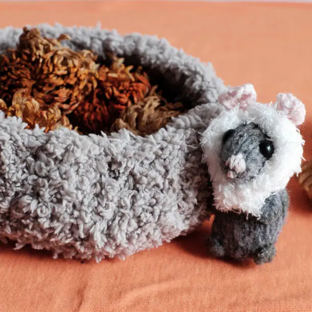 cute mice stand near basket of dried flower on orange  background, woolen small rat knit from yarn in free time of craftsmanship