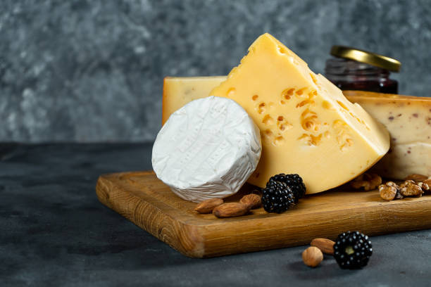 istock Cheese Assortment on a dark stone background with copy space. Different types: Camembert, cheese with spices, Dutch cheese on wooden cutting board. almond, blackberries and jam with cheese. Soft focus 1167326445
