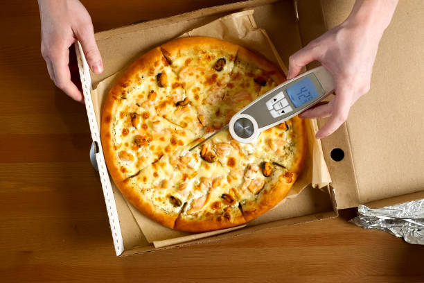measuring pizza temperature with a thermometer stock photo