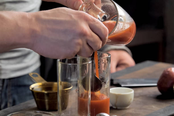 スプーンを通してグラスにトマトジュースを注ぎます。 - healthy eating red above studio shot ストックフォトと画像