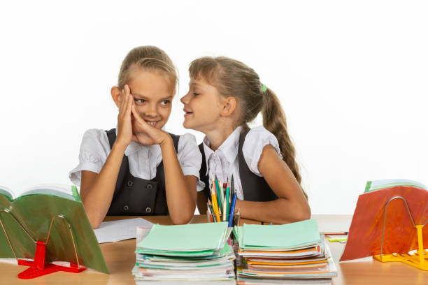 istock Girlfriend at school desk tells something interesting on the ear 1167332439
