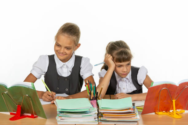 istock Two schoolgirls at a desk, one excellent student, the second two-year student 1167332459