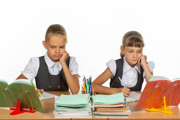 istock Sad schoolgirls look at a book in a lesson 1167332466