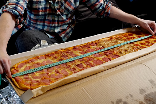 Long big sausage pizza. Measure pizza length with a tape measure