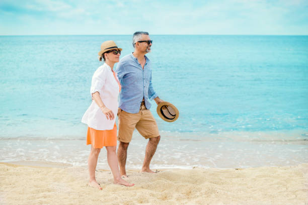 istock Happy mature couple walking along the beach 1167337941