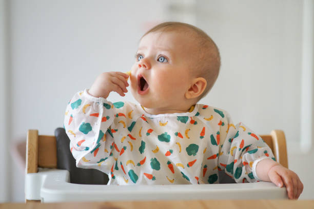 bebé comiendo su merienda ella misma - baby food fotografías e imágenes de stock