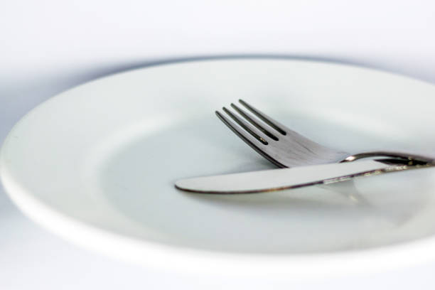 istock Knife and fork on white plate isolated on white background 1167341381