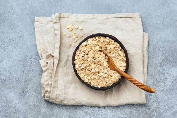 avena enrollada o copos de avena en cuenco de madera - oat wheat oatmeal cereal plant fotografías e imágenes de stock