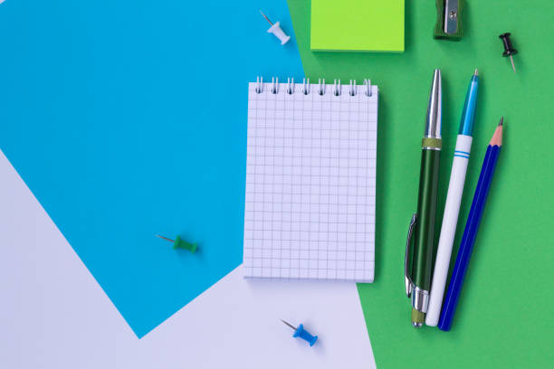 istock notebook and pencil isolated on white, blue and green background top view 1167348195