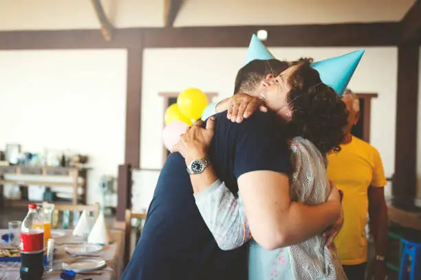 Grandmother and grandson embracing using party hat