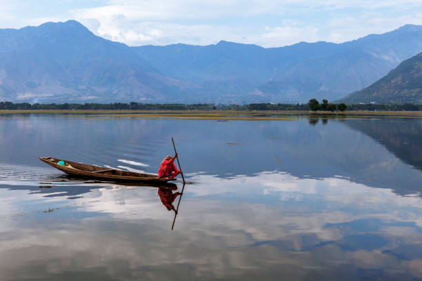 Scenic view of Dal lake, Jammu & Kashmir, India A local woman in red colour dress boating in dal lake for routing day today work lake nagin stock pictures, royalty-free photos & images