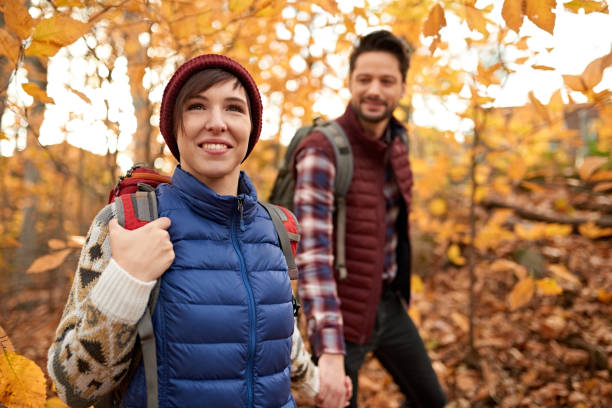 attractive caucasian couple hiking through the forest in the fall in canada - wood dirt road footpath exercising imagens e fotografias de stock