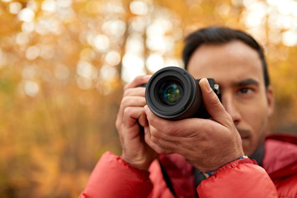 istock Attractive indian man taking pictures with a mirrorless camera through the forest in the fall in Canada 1167361412