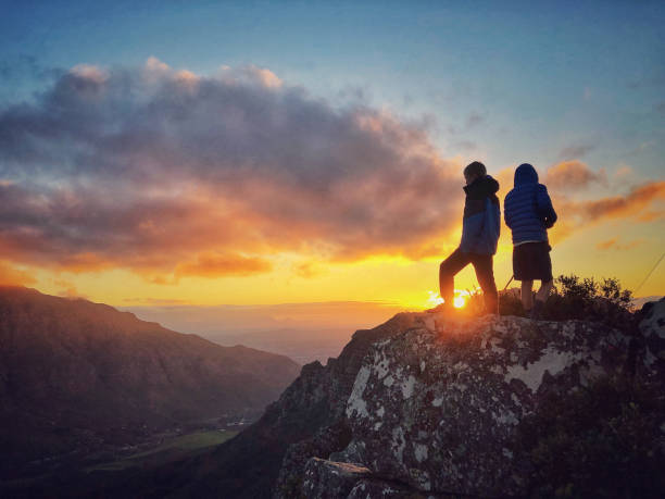istock Silhouette boys on mountain top at sunset looking away 1167367980