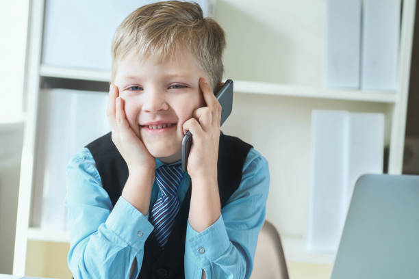 istock Smart little boy in suit working on computer, taking notes and speaking on the phone emotionally. 1167376600