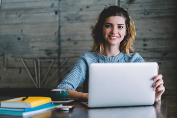 istock Portrait of successful female graphic designer smiling at camera while working on development of own internet store sitting at laptop computer.Positive prosperous student freelancer installing app 1167376905