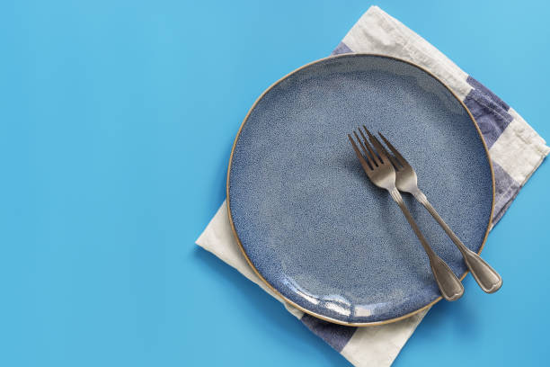 istock Flat lay empty plate, forks and napkin on a blue background. Top view, copy space. 1167377626