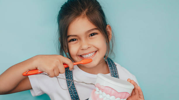 sonriendo chica mixta cepillado dientes en el fondo azul. - salud dental fotografías e imágenes de stock
