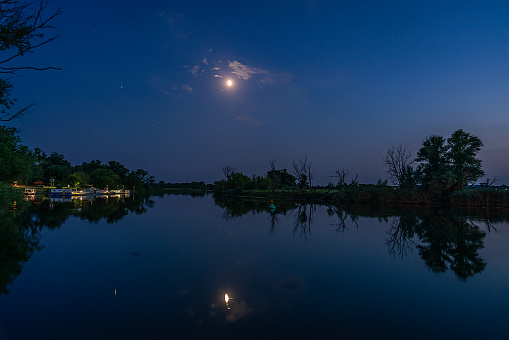 Nighshot of the harbour in Strodehne with moon reflecting on water of the river Havel in Havelaue, Brandenburg, Germany
