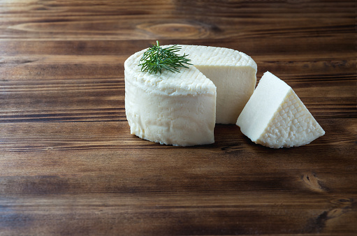 Homemade cheese and slice with dill on dark wooden background