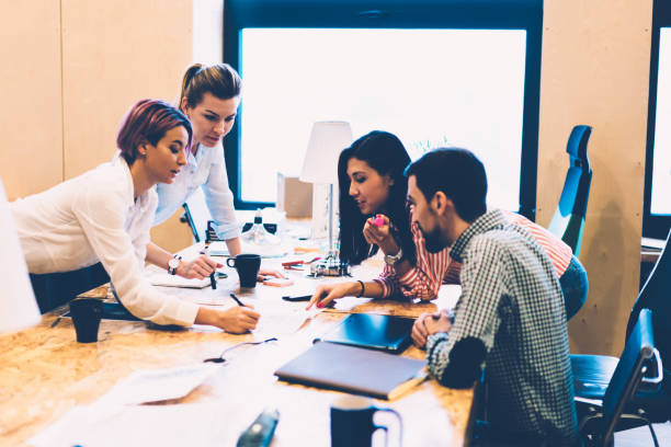istock Young skilled group of architects having brainstorming session in office share ideas for graphic, professional team of designers cooperating on project sitting at desktop with stationary and stuff 1167389950