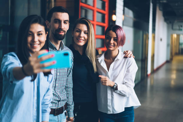 istock Young positive skilled group of employees having fun while taking together photo on smartphone camera for sharing in social network.Prosperous crew enjoying working break and making selfie on cellular 1167390070