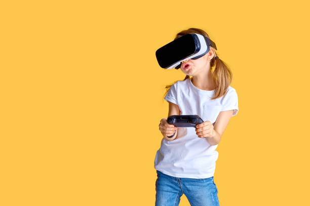 istock Girl experiencing VR headset vs joystick game on yellow background. Surprised emotions on her face. Child using a gaming gadget for virtual reality 1167391284