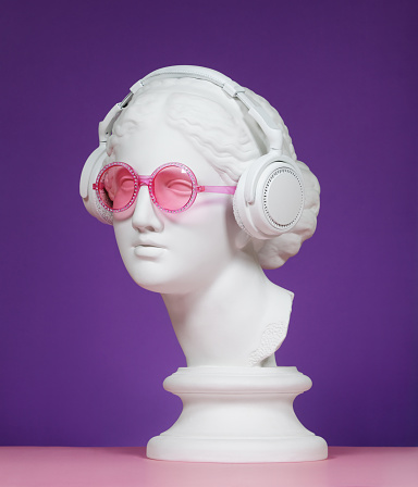 Plaster head model (mass produced replica of Head of Aphrodite of Knidos) wearing headphones and pink eyeglasses