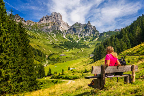 giovane donna seduta in panchina e vista sulle grandi bischofsmütze, monti dachstein, alpi - bench mountain park sitting foto e immagini stock