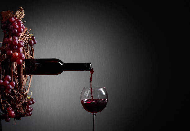 istock Red wine pouring from a bottle into a glass. 1167397896